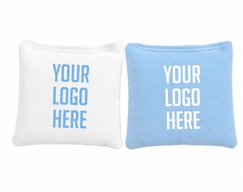 May include: Two square bean bags, one white with light blue text and one light blue with white text. Both bean bags feature the printed text YOUR LOGO HERE in a sans-serif font, centered on the front surface with visible stitching along the top edge.