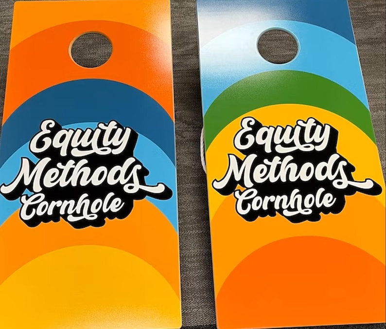 May include: Two rectangular cornhole boards featuring a circular hole at the top. The boards display a colorful arched design in orange, blue, and green. The text Equity Methods Cornhole is printed in a bold white script font with a black shadow.
