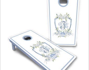 May include: A white cornhole set with blue trim and a floral design. The design features a monogram "B&C" and the date "June 22, 2024".
