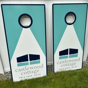 May include: Two teal blue and white wooden signs with the text "castlewood cottage" and "owls head, maine".