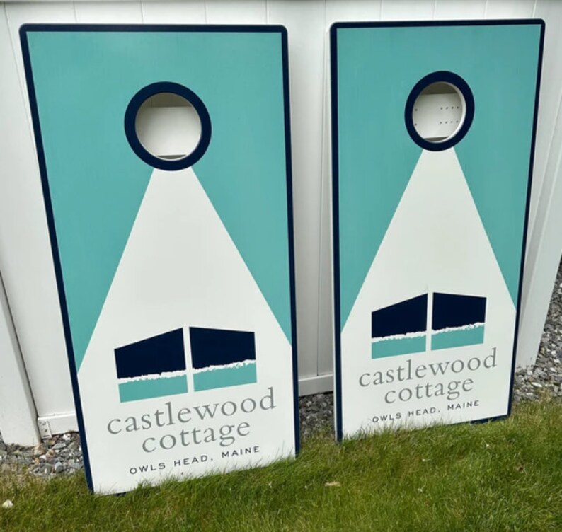 May include: Two teal blue and white wooden signs with the text "castlewood cottage" and "owls head, maine".