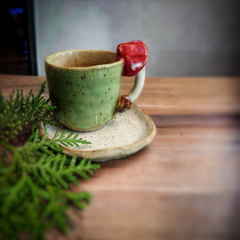 a cup with a mushroom on a cappucino white saucer