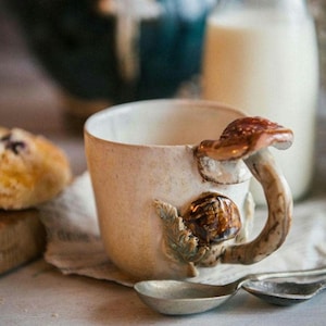 K&ouml;nnte beinhalten: Ein Set aus drei Keramikbechern mit gesprenkelter, matter Oberfl&auml;che. Die Becher sind in den Farbt&ouml;nen Creme, Hellgrau und Dunkelgrau gehalten. Jeder Becher hat ein schlichtes, minimalistisches Design, ideal f&uuml;r Kaffee oder Tee.