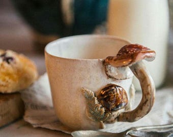 May include: A set of three ceramic mugs with a speckled, matte finish. The mugs are in shades of cream, light gray, and dark gray. Each mug has a simple, minimalist design, perfect for coffee or tea.