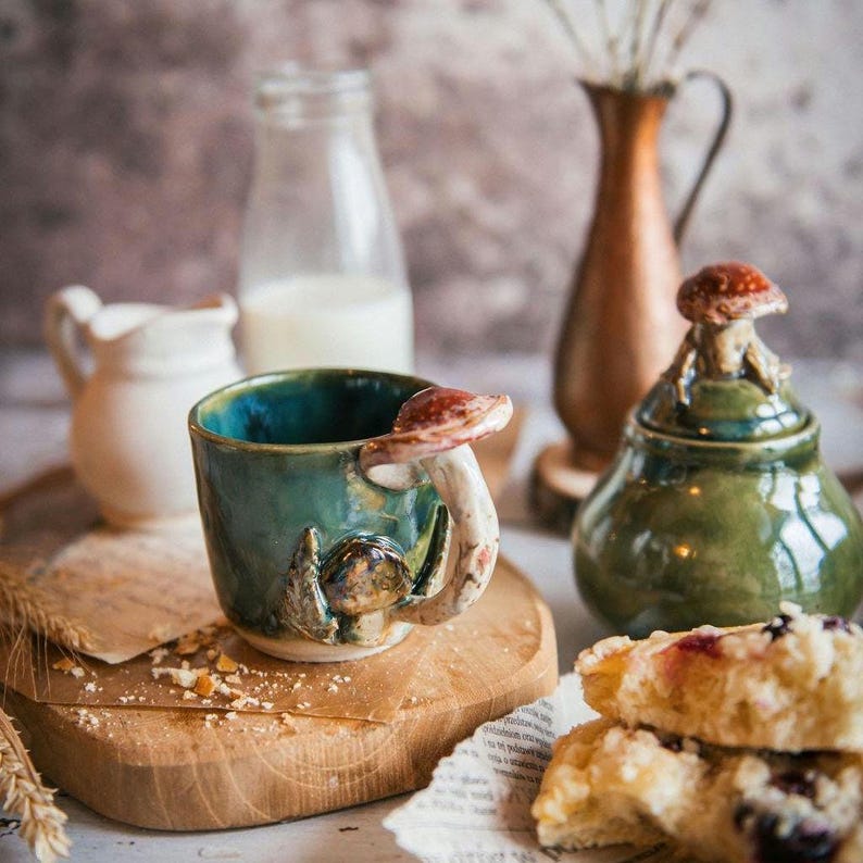 K&ouml;nnte beinhalten: Ein Set aus drei Keramikbechern mit gesprenkelter, matter Oberfl&auml;che. Die Becher sind in Creme-, Hellgrau- und Dunkelgraut&ouml;nen gehalten. Jeder Becher hat ein schlichtes, minimalistisches Design.