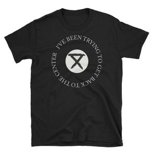 May include: Black t-shirt with a white circle graphic that says "I've been trying to get back to the center" with a stylized "X" in the center of the circle.