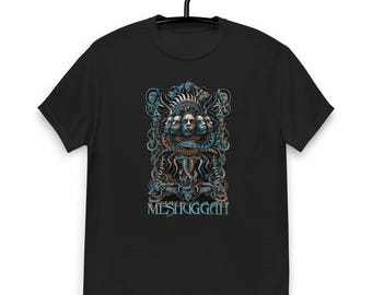 Może przedstawiać: Czarna koszulka z szczegółowym projektem graficznym. Projekt zawiera wiele twarzy, skomplikowane wzory i słowo "MESHUGGAH" w stylizowanej czcionce. Grafika jest renderowana w odcieniach niebieskiego, turkusowego i brązu.