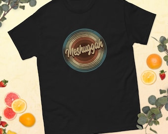 Może przedstawiać: Czarny T-shirt z retro grafiką płyty z napisem "Meshuggah" w kolorowym foncie.
