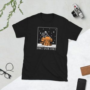 May include: Black t-shirt featuring a white graphic of a skeleton sitting on a mushroom with stars in the background. The text "Dance Gavin Dance" is printed below the graphic.