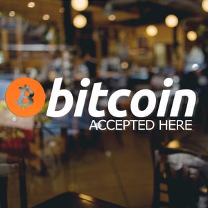 May include: A white sticker on a glass door with the text "bitcoin ACCEPTED HERE" and an orange bitcoin symbol.