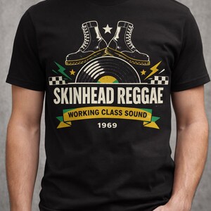 Może przedstawiać: Czarny t-shirt z grafiką. Projekt zawiera napis "SKINHEAD REGGAE WORKING CLASS SOUND 1969", parę butów, płytę winylową, błyskawice i gwiazdy.