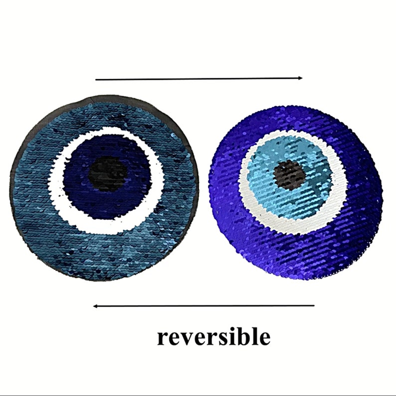 May include: Reversible sequin pillow with a blue evil eye design. One side is blue and white, the other side is purple and blue.