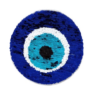 May include: A blue and white evil eye charm made of sequins. The eye is surrounded by a white circle and a blue circle.