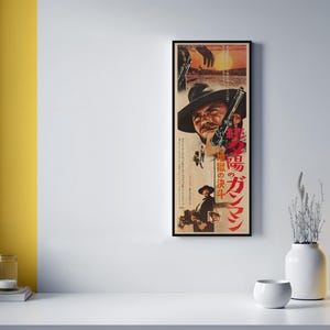 a framed poster of a man with a cowboy hat, displayed on a wall next to a white table with various decorative items, including a yellow vase and a small white bowl.