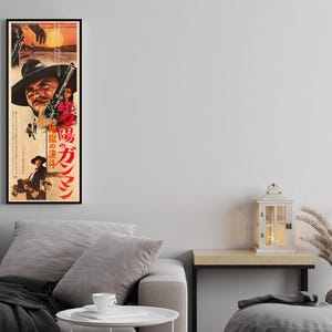 a living room with a gray sofa, a small table, and a decorative lantern. There is also a framed poster of a movie on the wall above the sofa.