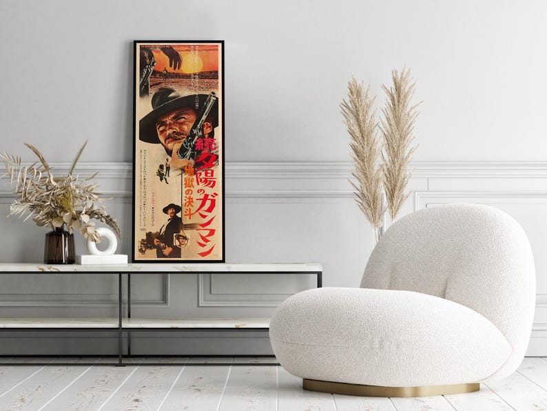 a poster of a man with a cowboy hat, a vase of dried flowers, and a white armchair in a living room setting.