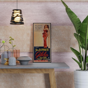 a vintage-style poster of a woman in a red dress, displayed on a wall above a wooden table with various decorative items such as vases, a bowl, and a potted plant.