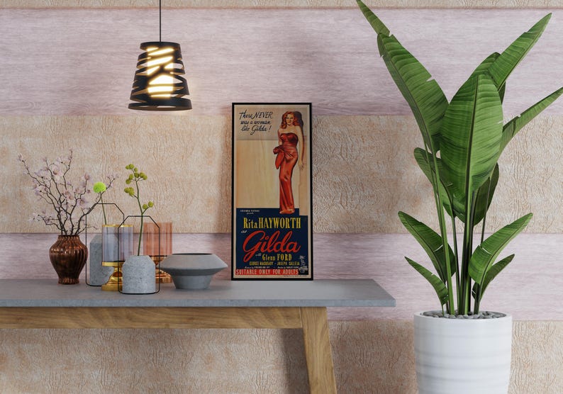 a vintage-style poster of a woman in a red dress, displayed on a wall above a wooden table with various decorative items such as vases, a bowl, and a potted plant.