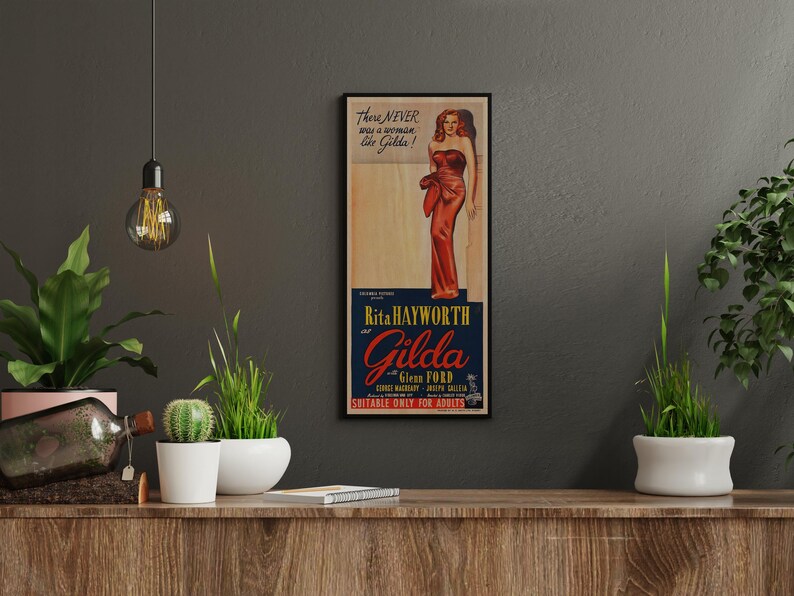 a framed vintage advertisement poster of a woman in a red dress, hanging on a wall above a wooden shelf with potted plants and other decorative items.
