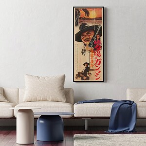 a living room with a large framed poster of a man on the wall, a white sofa, a blue side table, and a blue blanket on the sofa.