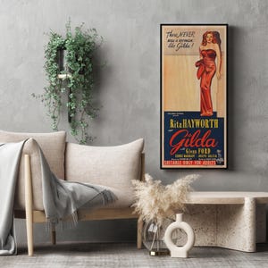 a living room setting with a sofa, a coffee table, and a potted plant. There is a framed poster of a woman in a red dress hanging on the wall, and a vase of flowers is placed on the coffee table.