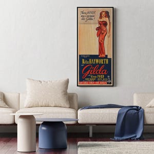 a living room with a white sofa, a blue table, and a framed poster of a woman in a red dress hanging on the wall.
