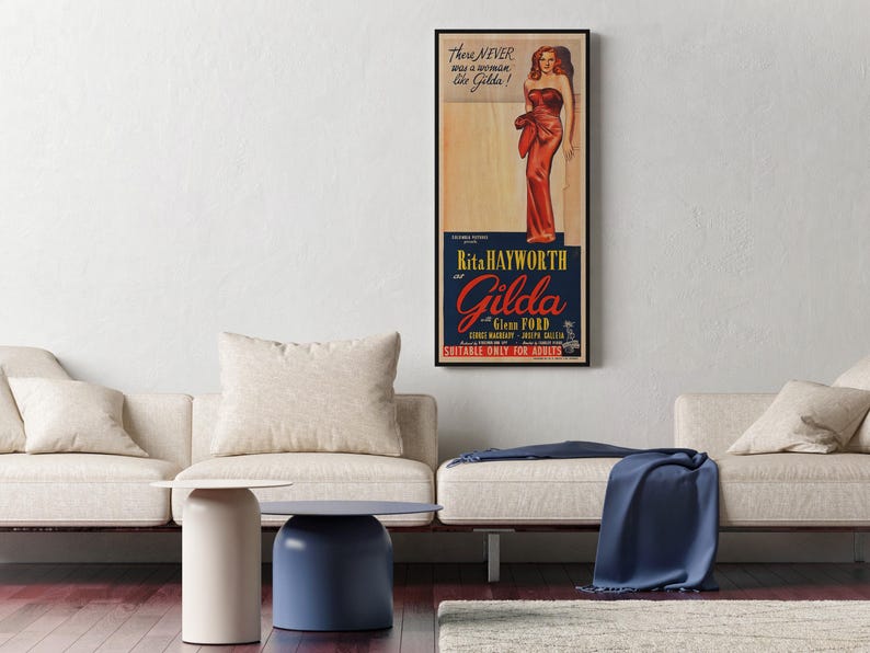 a living room with a white sofa, a blue table, and a framed poster of a woman in a red dress hanging on the wall.