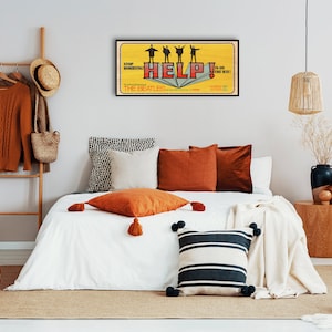 Puede incluir: Una cama blanca con una manta blanca y varias almohadas. Las almohadas son de color naranja, marr&oacute;n y rayas blancas y negras. Hay un p&oacute;ster enmarcado en la pared detr&aacute;s de la cama que dice "Help!" y presenta una banda de cuatro personas. El p&oacute;ster es amarillo y rojo.