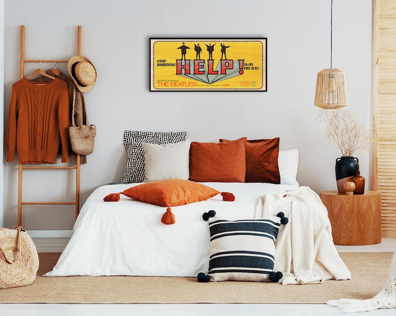 Puede incluir: Una cama blanca con una manta blanca y varias almohadas. Las almohadas son de color naranja, marr&oacute;n y rayas blancas y negras. Hay un p&oacute;ster enmarcado en la pared detr&aacute;s de la cama que dice "Help!" y presenta una banda de cuatro personas. El p&oacute;ster es amarillo y rojo.