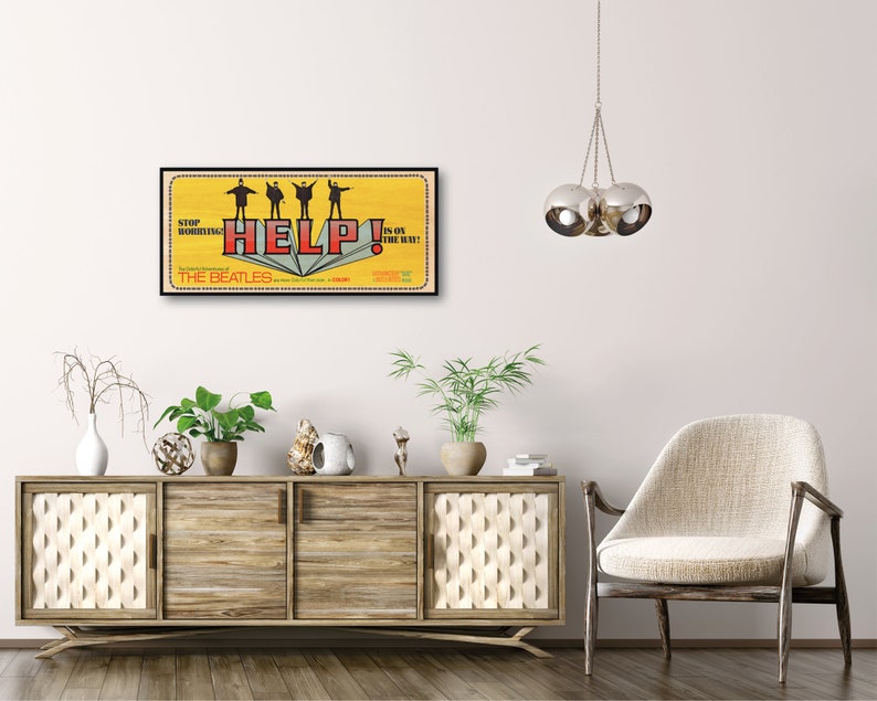 Puede incluir: Un p&oacute;ster de estilo vintage para la pel&iacute;cula de los Beatles "Help!" de 1965. El p&oacute;ster presenta un fondo amarillo con la palabra "HELP!" en letras rojas y los Beatles de pie sobre un libro. El texto "STOP!" y "IS ON THE WAY!" est&aacute; en letras negras.