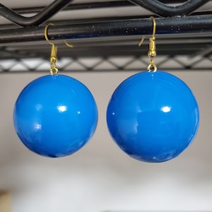 May include: A pair of blue, round, shiny earrings with gold hooks.