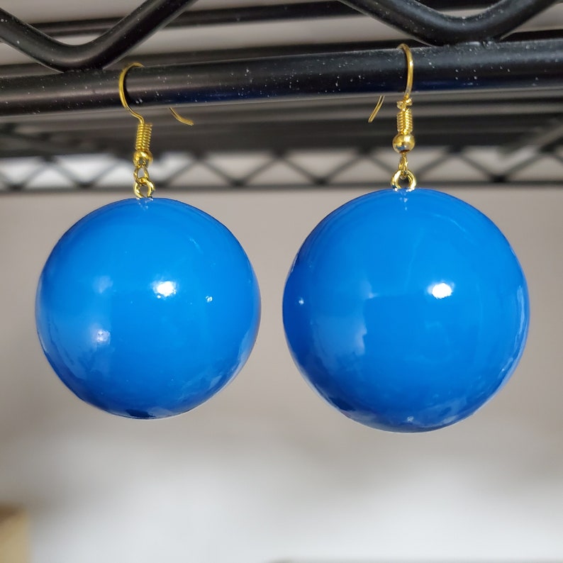 May include: A pair of blue, round, shiny earrings with gold hooks.