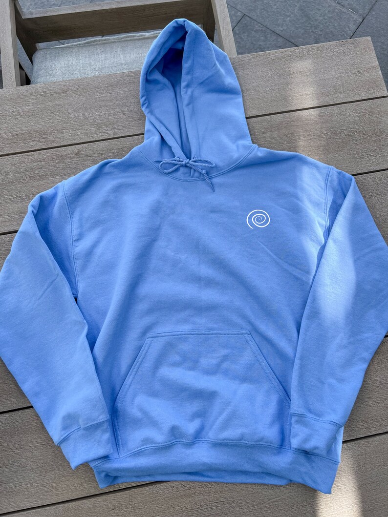 Peut inclure: Un sweat-shirt &agrave; capuche bleu clair avec un motif en spirale blanc sur le devant. Le sweat-shirt a une poche kangourou et une capuche &agrave; cordon.