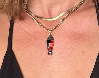 Colgante de collar con colgante de pez sardina en rojo mate, negro y dorado, hecho a mano con cuentas tejidas.