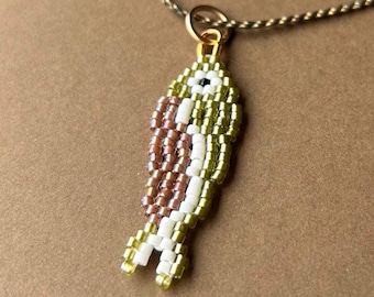 Colgante de collar con colgante de pez sardina en cuentas verdes y marrones, hecho a mano con cuentas de semillas tejidas.