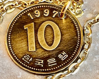 May include: A gold-coloured coin with the number 10 in large numerals, the year 1997, and Korean text. The coin is attached to a gold chain.