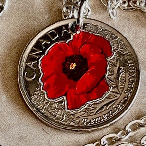 May include: A silver chain necklace with a Canadian quarter coin pendant. The coin features a red poppy with a black center and the words "Canada" and "Remember" on the coin.