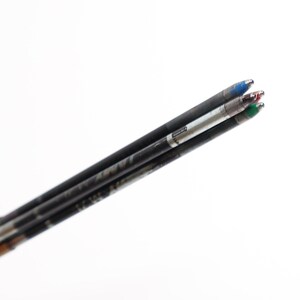 Puede incluir: Primer plano de varios recambios de bol&iacute;grafo negros con puntas de tinta azul, roja y verde. Los recambios est&aacute;n angulados hacia la esquina superior derecha sobre un fondo blanco. Los bol&iacute;grafos est&aacute;n en un portal&aacute;pices negro.