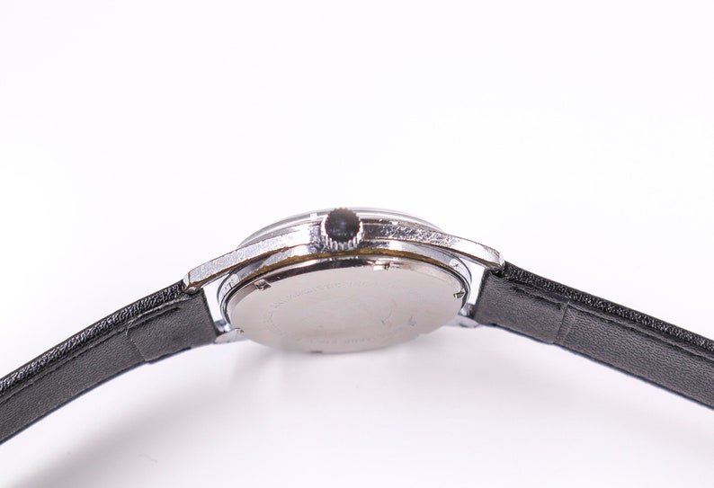 May include: A silver wristwatch with a black leather band. The watch has a round face and a silver case.