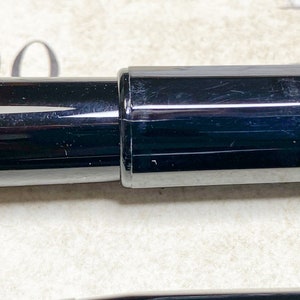 K&ouml;nnte beinhalten: Ein schwarzer F&uuml;llfederhalter mit silberner Klammer und schwarzer Kappe. Der Stift ist geschlossen und die Kappe ist auf dem Stift.