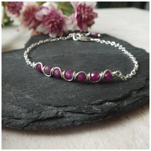 May include: A silver chain bracelet with a row of pink gemstone beads wrapped in silver wire.