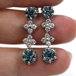May include: A pair of silver dangle earrings with blue and white gemstones. The earrings feature a cluster of blue gemstones at the bottom, followed by two clusters of white gemstones, and then a final cluster of blue gemstones at the top.