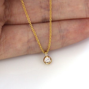 May include: A delicate gold chain necklace with a small, round, bezel-set diamond pendant.
