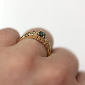 May include: A gold ring with a green gemstone and small white gemstones set in a floral design.