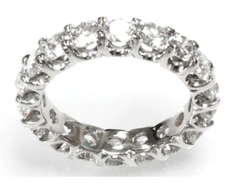May include: A silver eternity band with a row of round, clear diamonds set in a continuous circle.