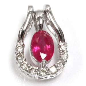 May include: A silver pendant with a large oval ruby gemstone surrounded by a halo of smaller diamonds.