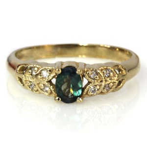 May include: A gold ring with a green oval gemstone surrounded by small diamonds set in a leaf design.