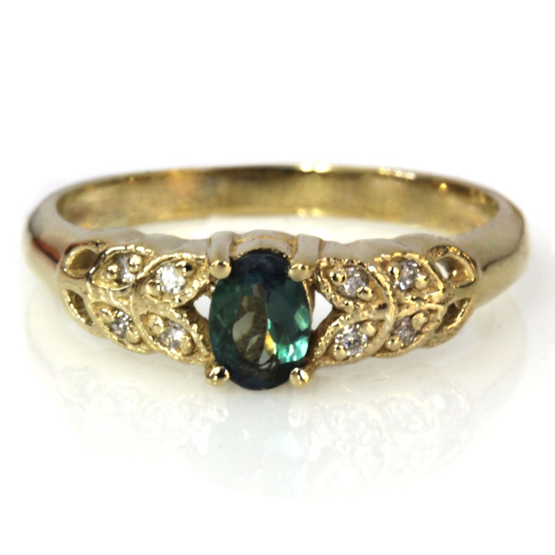 May include: A gold ring with a green oval gemstone surrounded by small diamonds set in a leaf design.