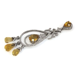 May include: A silver dangle earring with a pear-shaped yellow gemstone and smaller yellow gemstones hanging from the bottom.