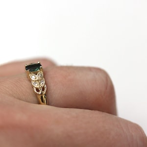 May include: A gold ring with a green gemstone and small white gemstones set in a leaf design.